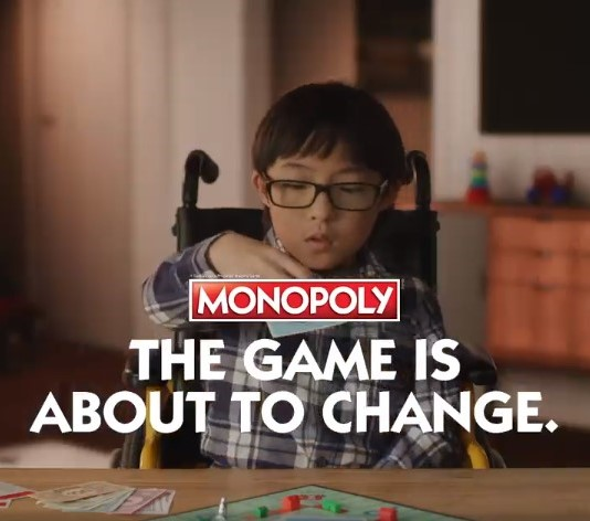 A kid sits on a wheel chair and is playing Monopoly game. A kid sits on a wheel chair and is playing Monopoly game.